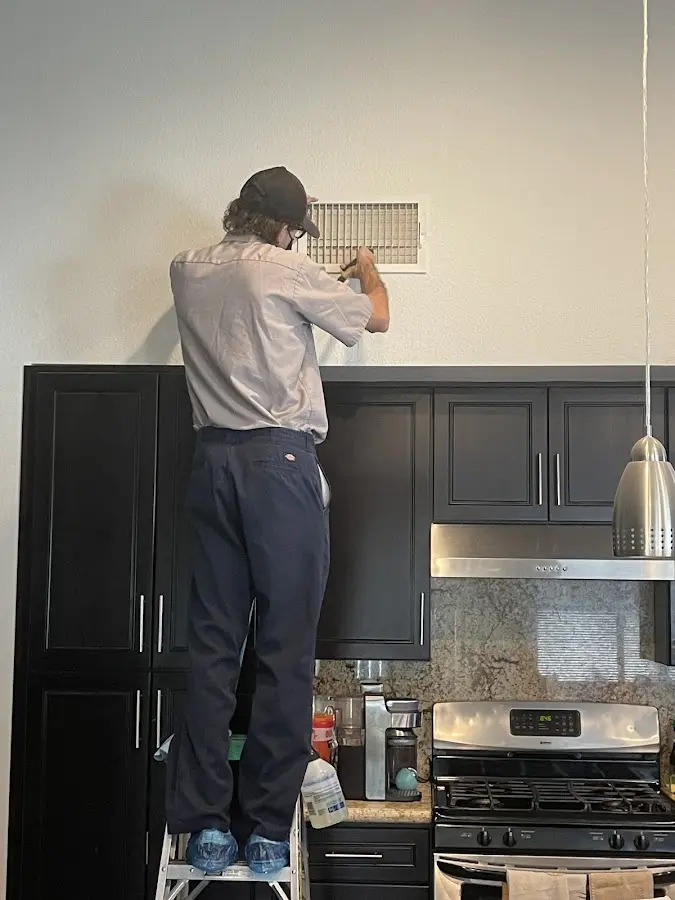 Technician inspecting an air vent during HVAC service in Country Club